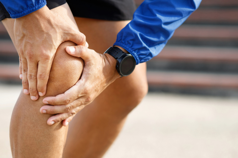 Knee pain in Markham depicted by a person holding their knee in pain, illustrating potential sports injury or joint discomfort.